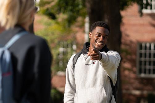 Beloit student outside, pointing and smiling at class mate.